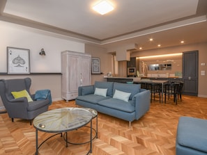 Un salon comprenant un canapé, un fauteuil et une table basse avec un plateau en verre.
