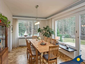 En matplats med ett träbord och stolar, stora fönster och utsikt över omgivningen.