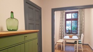 A room with a green cabinet, a window with patterned curtains, and a table with chairs. - Fewo Moltke Villa - Moltke Villa (Teterow)
