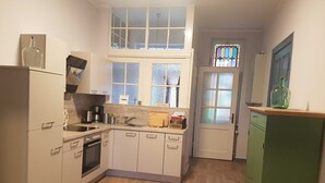 A compact kitchen with white cabinets, a wooden countertop, and a green cabinet. There is a window with frosted glass and a door with a stained glass window. - Fewo Moltke Villa - Moltke Villa (Teterow)