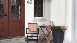 A front door with a number '42' above it, a chair, a small table, and a potted plant. - Fewo Moltke Villa - Moltke Villa (Teterow)