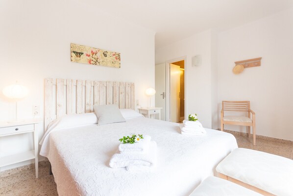 Ein Hotelzimmer mit Bett, Holz-Kopfstück, einem kleinen Tisch, einem Stuhl und einem Wandregal.