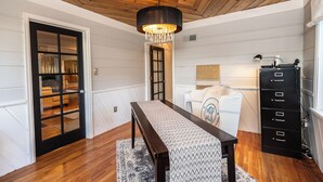 Ein Zimmer mit Holzboden, einer Kristallleuchter, einer Bank, einem Schminktisch und einer Tür zu einem weiteren Raum.