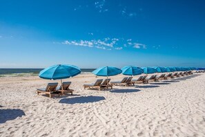 Una playa con filas de tumbonas y sombrillas azules.