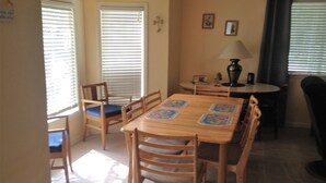 A dining area with a wooden table and chairs, a lamp, and a window with blinds.