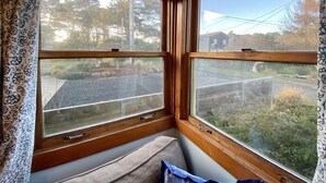 A corner room with two windows, a bench, and a view of a residential street.