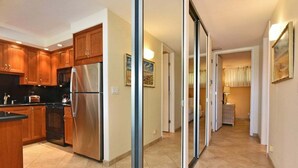 A modern kitchen with wooden cabinets, a stainless steel refrigerator, and a black countertop.