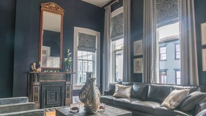 A dark-themed living room with a fireplace, a sofa, a coffee table, and a large mirror.