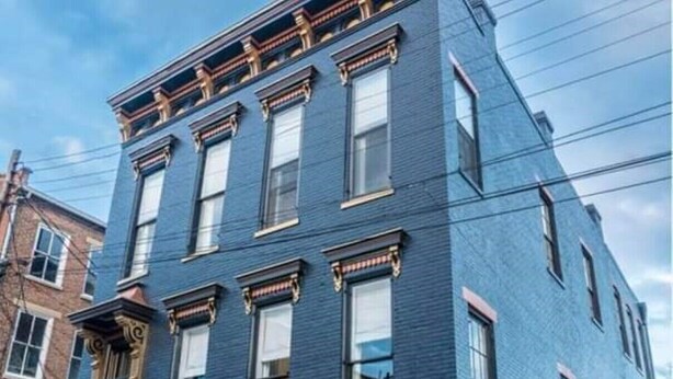 A multi-story building with a blue facade, large windows, and a traditional architectural style.