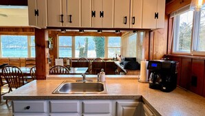 Cocina con armarios blancos, encimera de granito y cafetera.