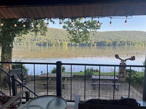 Una terraza con vista a un lago, rodeada de vegetación y una escultura de ciervo.