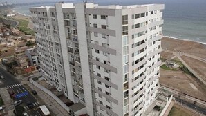Un edifici alt amb diverses plantes, una zona d'aparcament al davant i vistes a l'oceà.