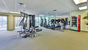 Et fitnesscenter med forskellig træningsudstyr, herunder løbebånd og styrkemaskiner, samt en automater.