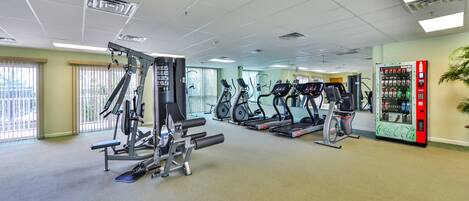 Une salle de sport équipée de divers appareils d’exercice, notamment des tapis de course et des appareils de musculation, ainsi qu’un distributeur automatique.