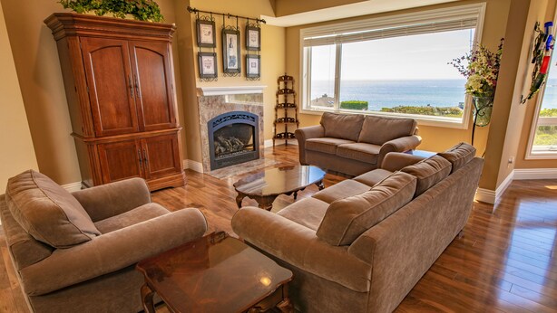 A living room with a fireplace, a large window with a view of the ocean, and a large wooden cabinet. - Luxury, Full Views, 6 Bedrooms/5 Full Baths, 3,800+ s.f., Pool Table, Hot Tub (Bodega Bay)