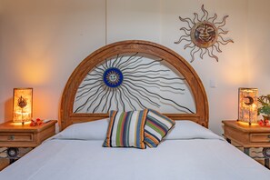 A bed with a wooden headboard, a colorful striped pillow, and two bedside tables with lamps. - Beautiful Beachfront Condo! Amazing View! Great rates! (Playa Del Carmen)