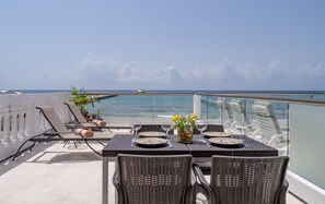 A balcony with a table set for two, overlooking the sea. - Beautiful Beachfront Condo! Amazing View! Great rates! (Playa Del Carmen)
