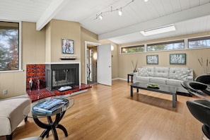A modern living room with a fireplace, a sofa, a coffee table, and large windows. - Private Contemporary Luxury Pebble Beach Home with Ocean Views (Pebble Beach)