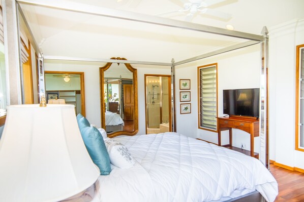 A bedroom with a large bed, a TV, a mirror, and a wardrobe.