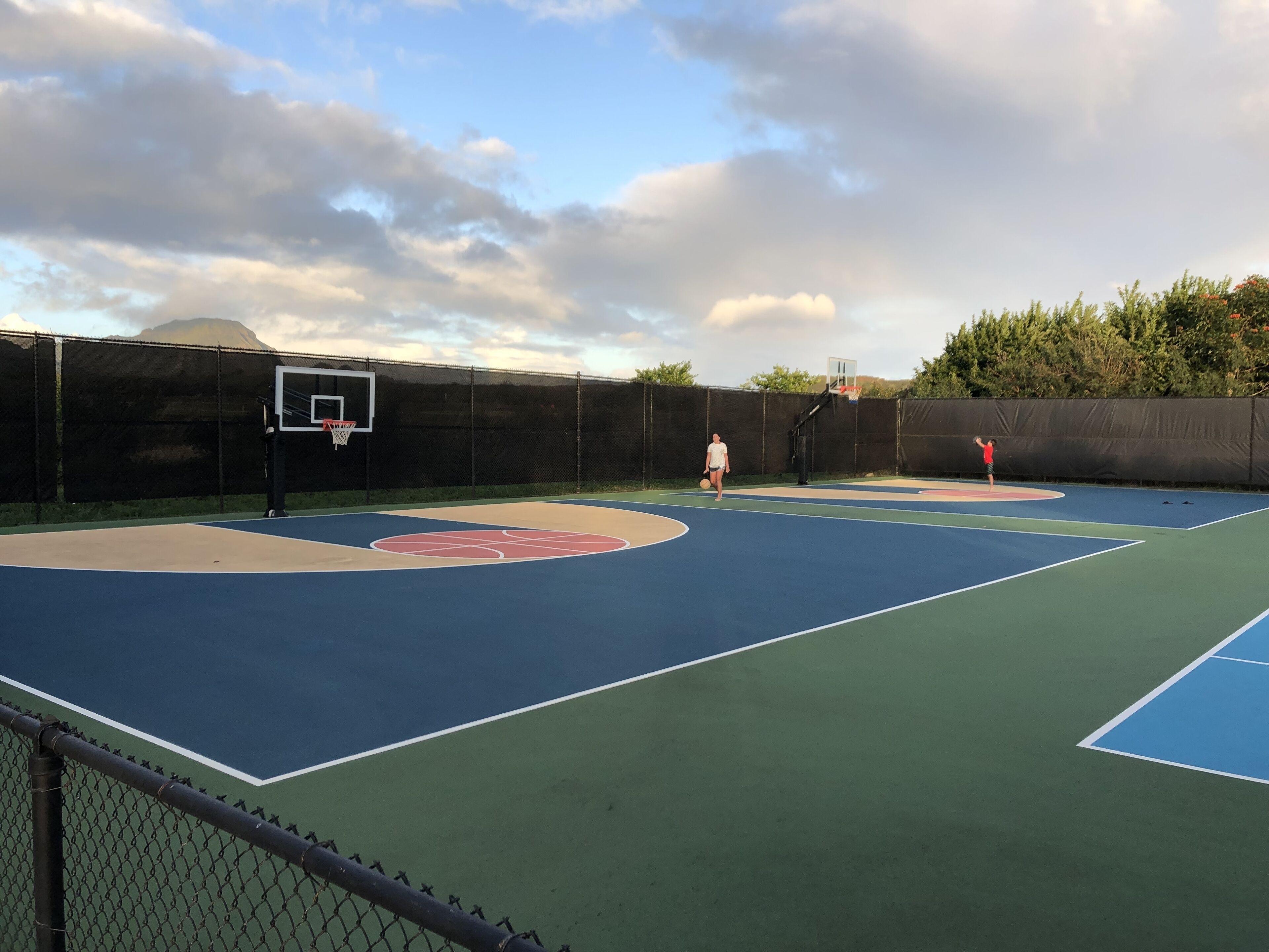 Ein Basketballplatz mit Korb, umgeben von einem Maschendrahtzaun.