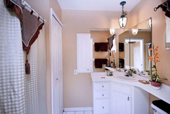 A bathroom with a white vanity, a mirror, and a hanging light fixture.