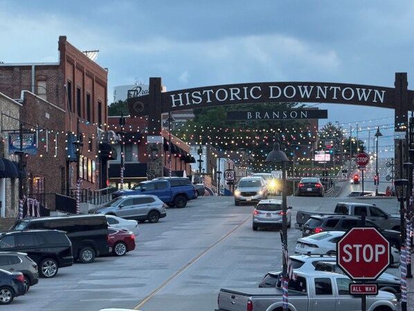 A street view with a historic downtown sign, cars parked along the street, and a stop sign.