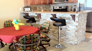 Una cocina con armarios de madera, encimera de granito y una isla integrada con taburetes de bar.