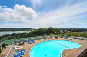 Une piscine dotée de chaises longues et offrant une vue sur un lac et des collines.