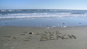 A beach with the words "I LOVE THIS BEACH" written in the sand.