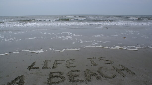 A beach with the words "LIFE IS BEACH" written in the sand.