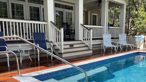 Una piscina con un deck de madera y un área de descanso techada con sillas y una mesa.