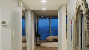 Un couloir d’hôtel donnant sur la mer, un grand miroir et un lit avec vue.