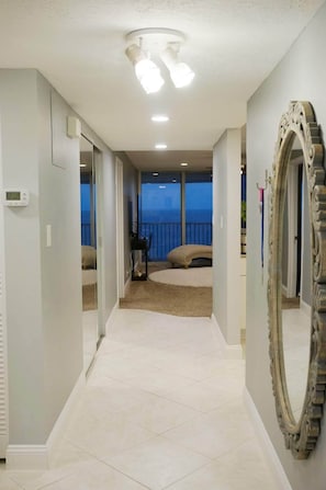 Enjoy ocean views from the balcony, featuring a large mirror, ceiling light and a small table with chair.
