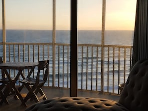 Enjoy the ocean view from this room's large window, featuring a comfortable sofa and dining area.