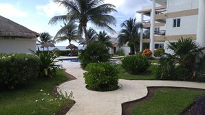 Un resort con piscina, palmeras y un edificio de techo de paja.
