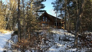 A cabin surrounded by trees with a snow-covered ground. - Log Cabin on beautiful Howard Lake. (Akeley)