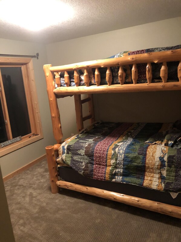 A bunk bed with a wooden frame and a colorful quilt.