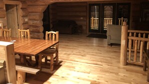 A log cabin interior with a wooden dining table, chairs, and a sofa. - Log Cabin on beautiful Howard Lake. (Akeley)