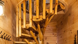 En trappe i træ med spiralform og design som en naturlig træstamme, indbygget i en hytte.