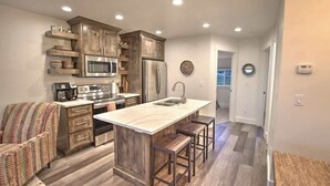 Une cuisine moderne avec des meubles en bois, des appareils électroménagers en acier inoxydable et un îlot central doté de tabourets.