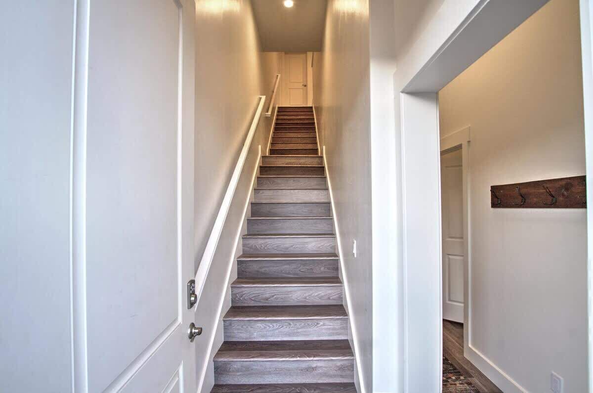 Un couloir étroit avec un escalier en bois menant à une porte au fond.