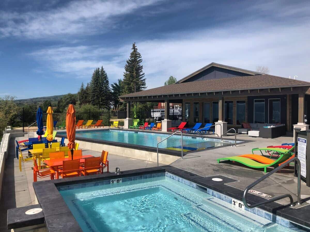 Un área de piscina con dos piscinas, sillones de descanso y sombrillas.