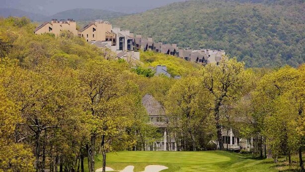 Ein Golfplatz mit Clubhaus und mehreren Gebäuden an einem Hügelhang.