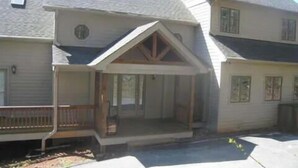 Ein zweistöckiges Haus mit überdachter Veranda, Garage und kleinem Vorgarten.