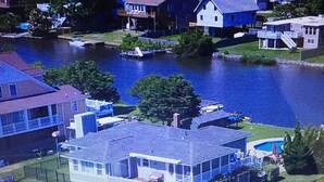 Ett modernt hus i två våningar med en stor framträdgård, en swimmingpool och en brygga vid vattnet.