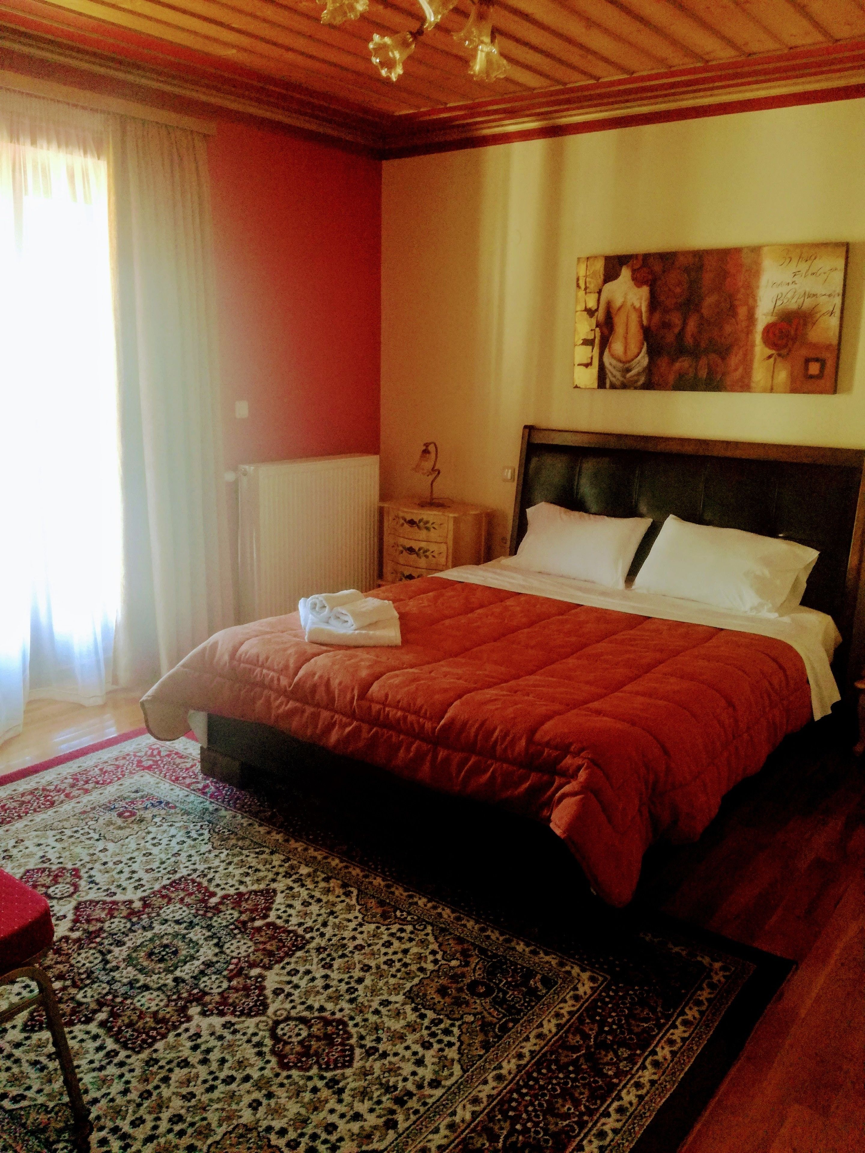 Une chambre à coucher avec un grand lit, une table de chevet, un tableau au mur et un tapis à motifs.
