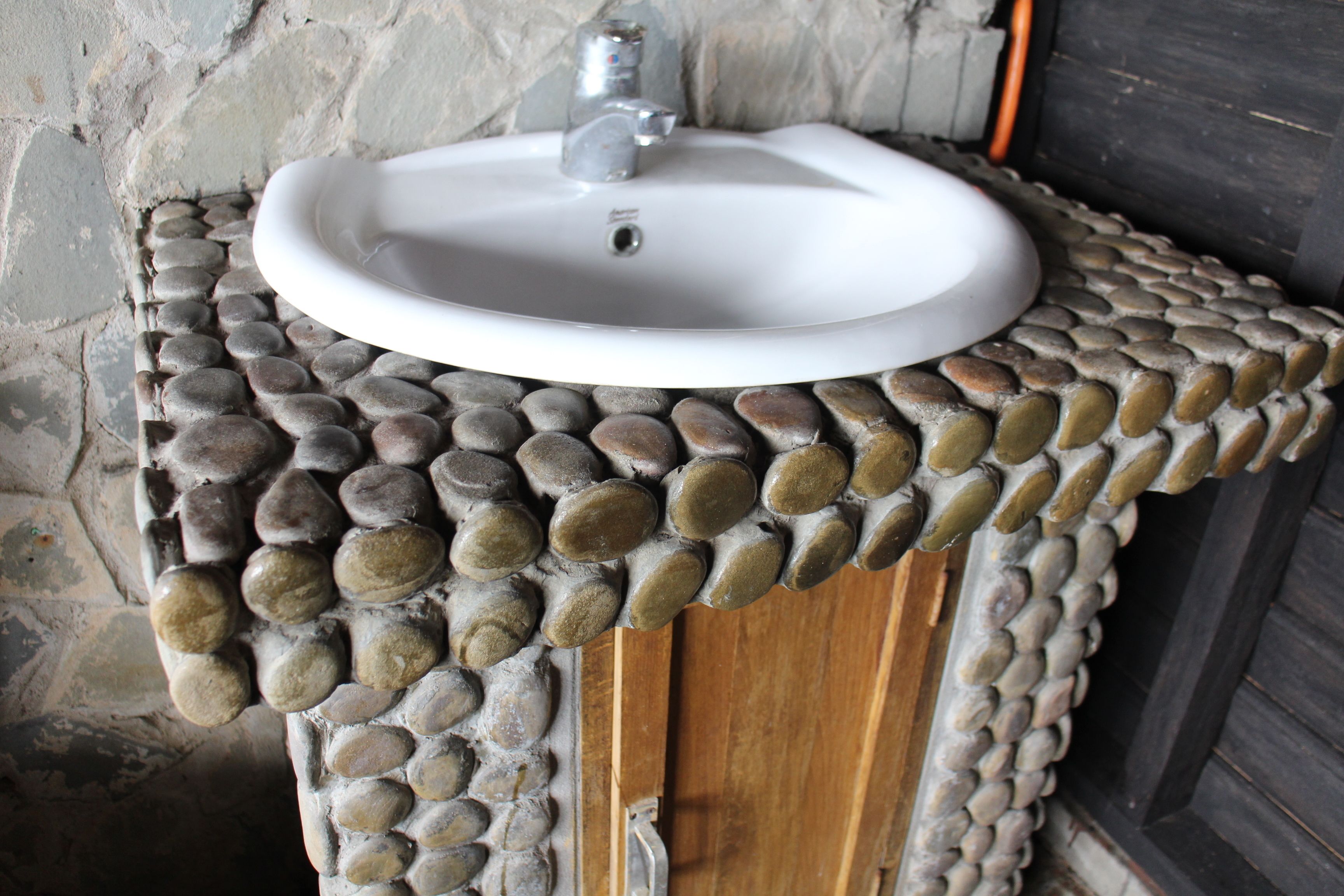 Un bagno con un lavabo in pietra e un piano d'appoggio in legno.