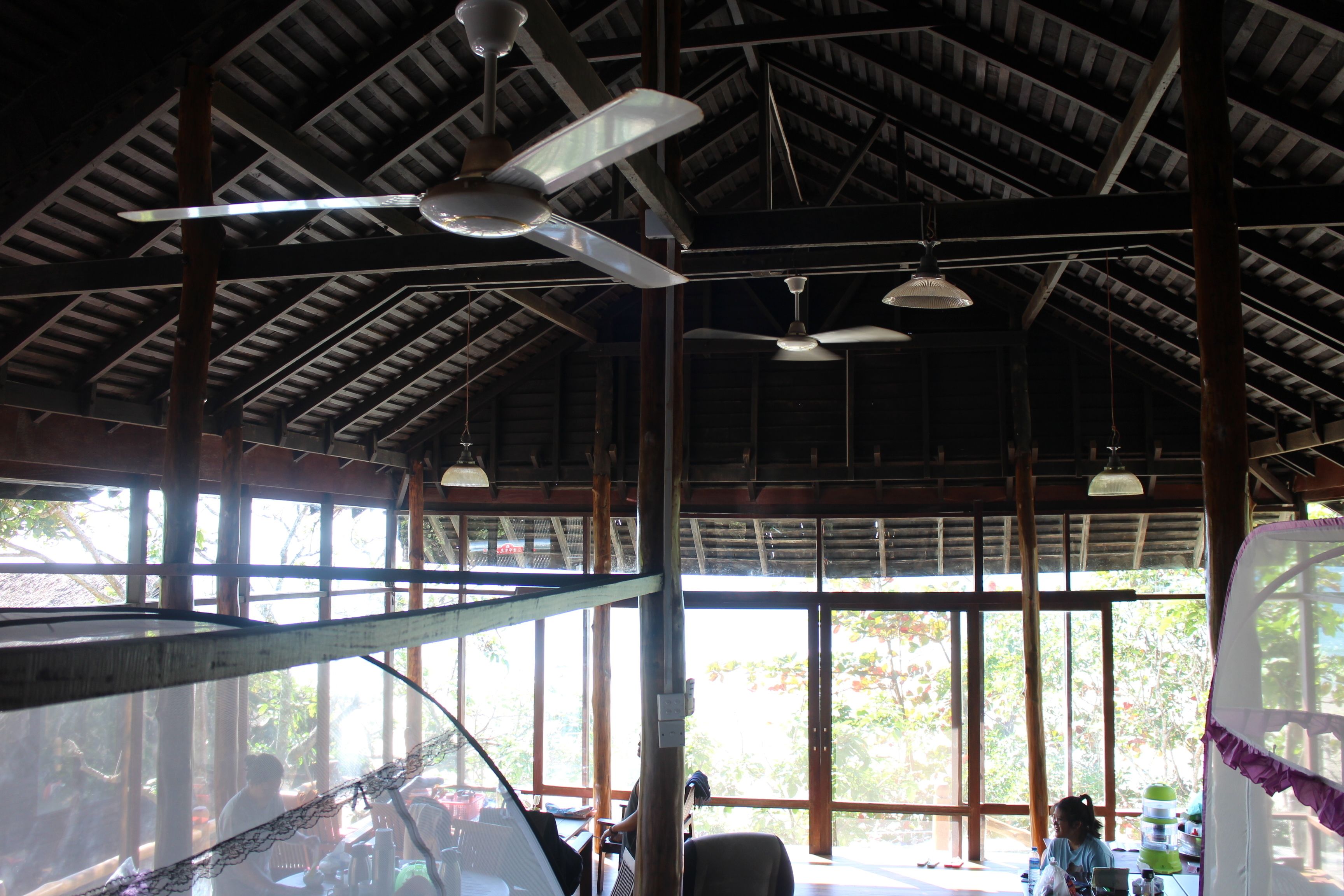 Una habitación amplia con techo alto, ventanas grandes y ventiladores de techo.