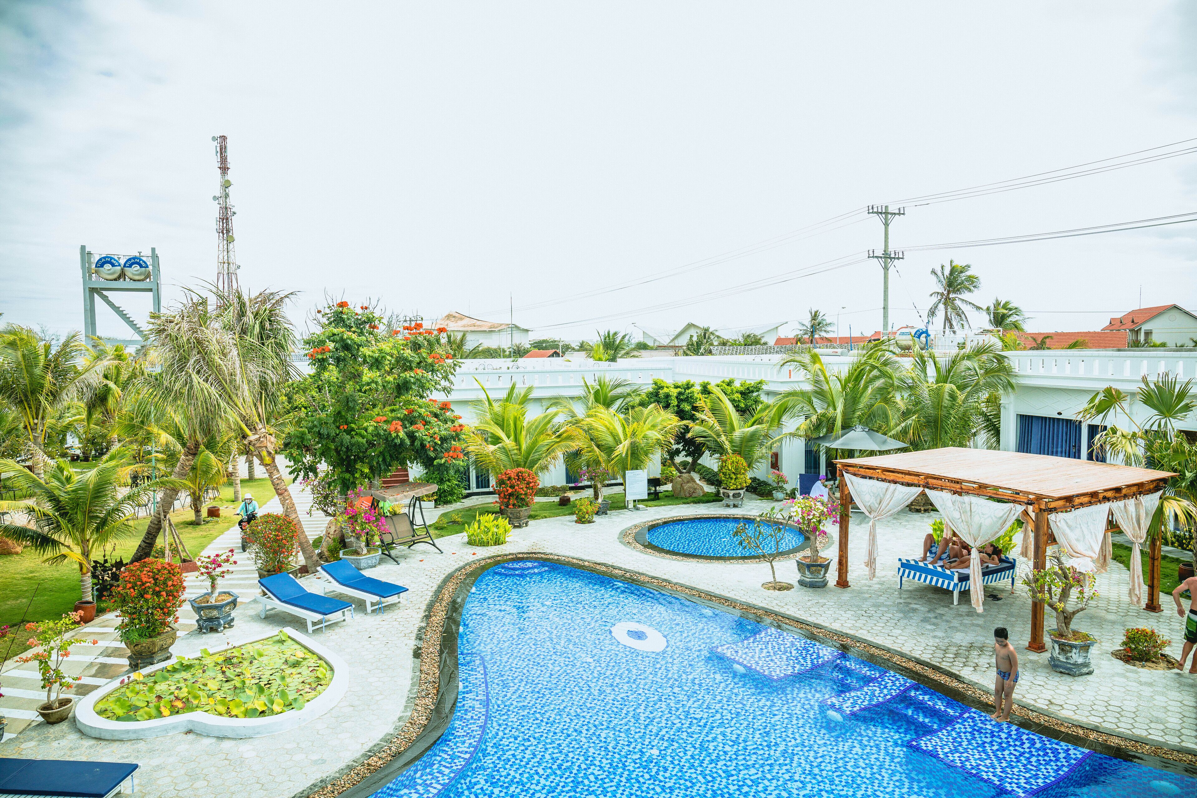 A pool area with two pools, lounge chairs, and a gazebo.