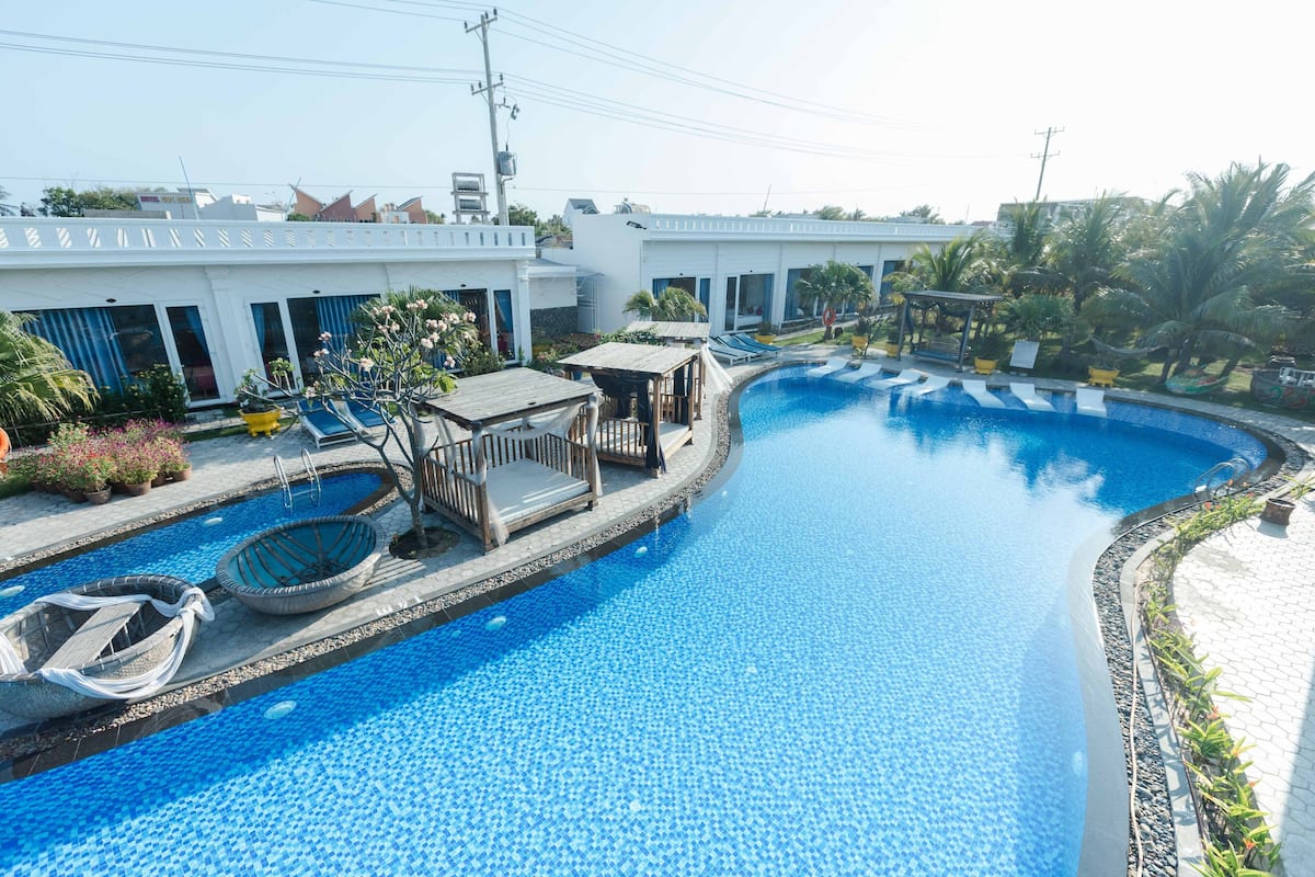 Una piscina con bordo in legno, sedie a sdraio e una piccola imbarcazione.